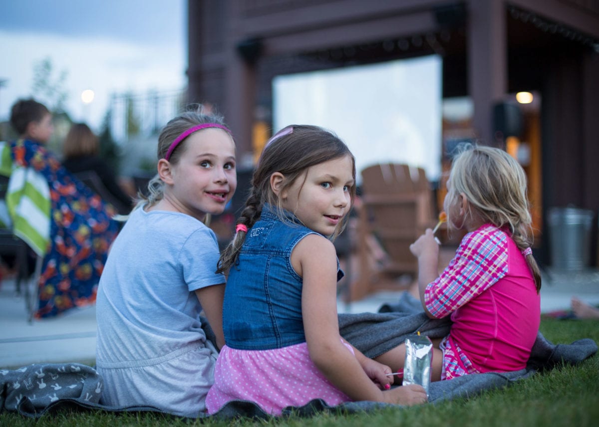 little girls sitting on the lawn for movie night